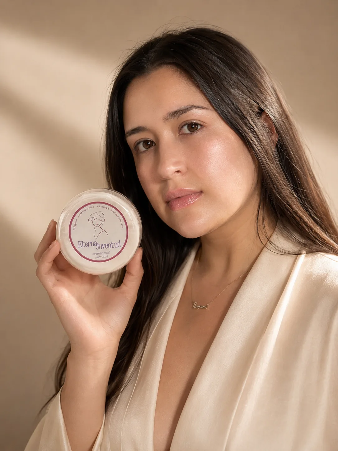 Mujer sosteniendo el frasco de crema Eterna Juventud junto a su rostro